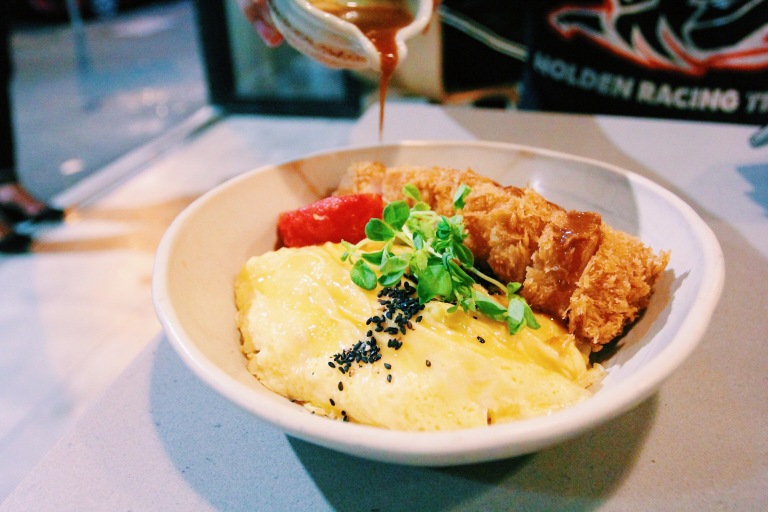 Tonkatsu: rice w/onion & onsen egg, free range scrambled eggs, apple mustard mayo, roasted tomatoes, red cabbage, miso sesame sauce – $23